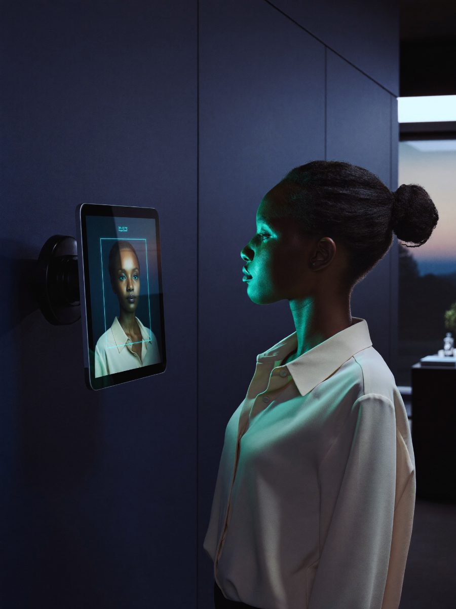 A woman verifying her identity by face at a wall-mounted BioVerify terminal